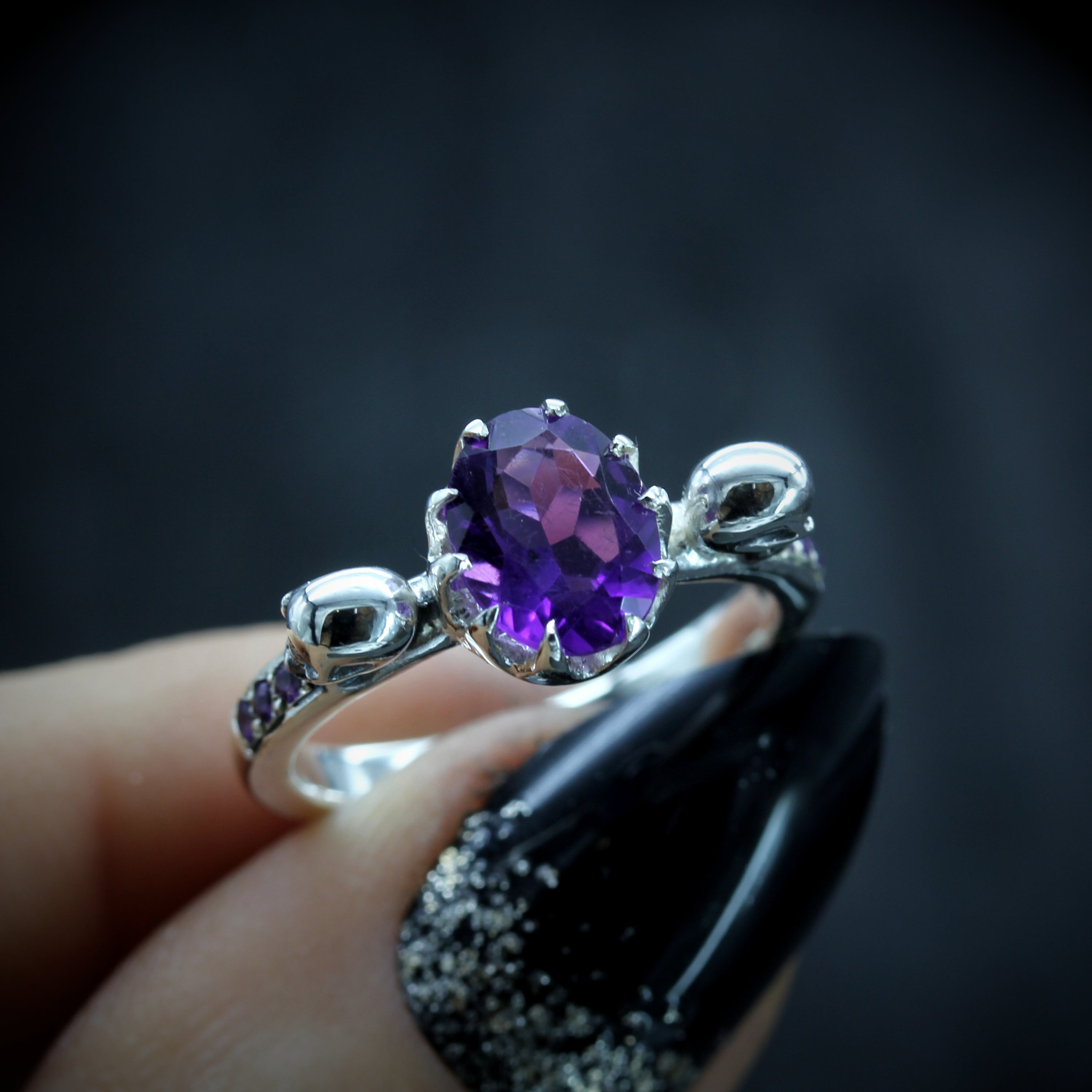 Oval Amethyst Silver Skull Engagement Ring held in Fingers