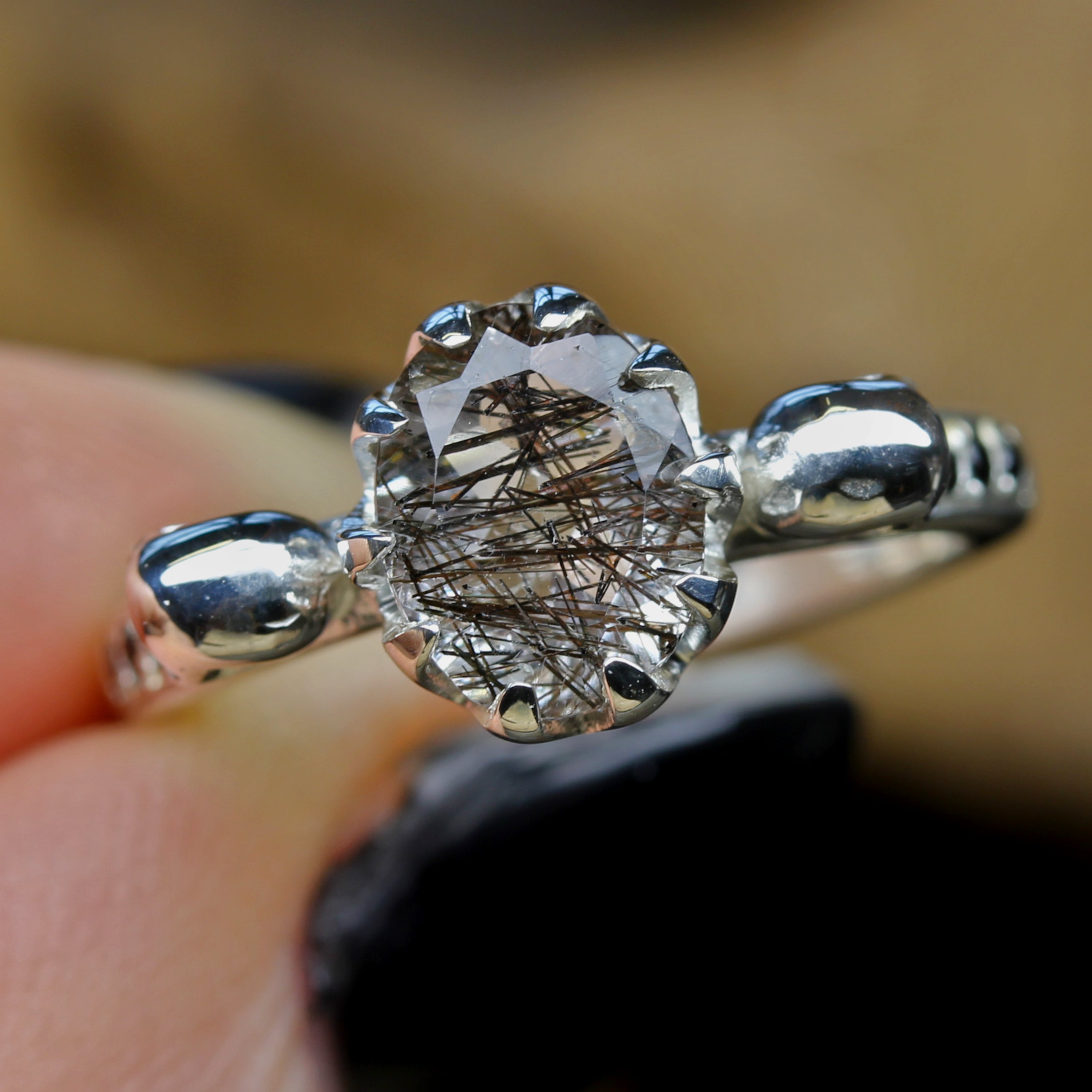 Oval Tourmalated Quartz Skull Engagement Ring being held in between fingers